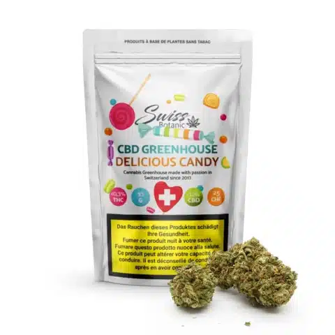 Un sachet blanc étiqueté "fleurs de cbd greenhouse delicious candy - 0. 3% thc" présente des graphiques colorés de bonbons, des détails de cannabis et des bourgeons de cannabis à l'avant, reflétant l'essence de la variété delicious candy.