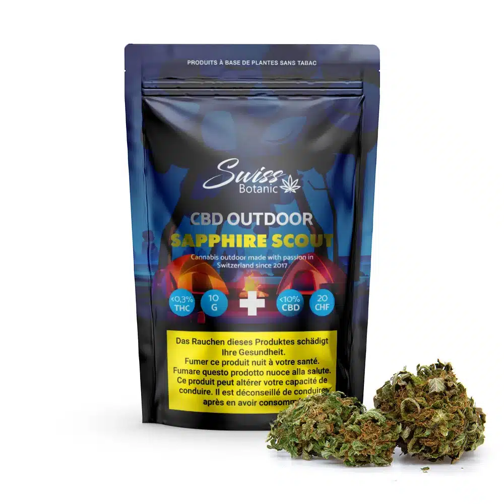 Fleurs de cbd outdoor sapphire scout – 0. 3% thc 1 Un paquet de fleurs de cbd outdoor sapphire scout - 0,3% thc avec des bourgeons de cannabis sur le devant, avec les détails de la variété, la teneur en thc et un avertissement sanitaire en allemand.