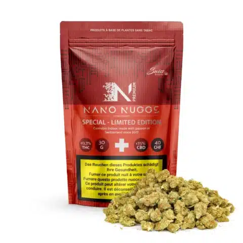 Un sachet refermable rouge étiqueté "fleurs de cbd indoor nano nuggs - special limited edition - 0. 3% thc" est photographié derrière une pile de bourgeons de cannabis séchés, avec les pourcentages de thc et de cbd ainsi que les avertissements sanitaires visibles sur l'emballage.