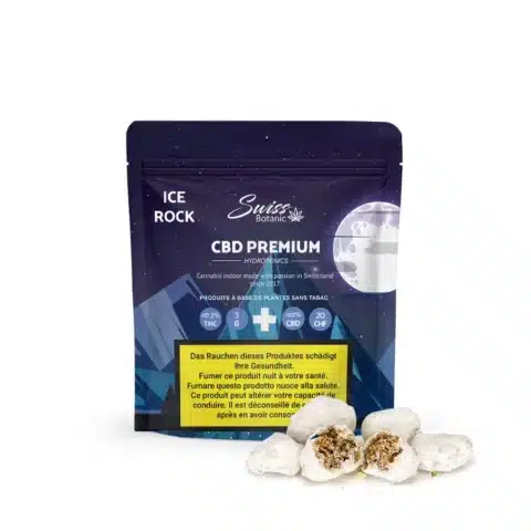 Un paquet bleu et violet de fleurs de cbd indoor icerock - 0,3 % thc se tient debout, avec trois morceaux de cbd blancs, semblables à des pierres, à l'avant - l'un d'entre eux est ouvert pour montrer son intérieur.