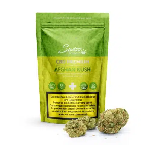 Un paquet vert de swiss botanic fleurs de cbd afghan kush d'intérieur - 0. 3% thc se tient debout avec des bourgeons de cannabis afghan kush disposés devant lui sur un fond blanc.