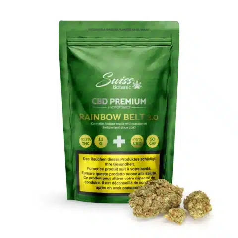 Un paquet de fleurs de cbd indoor rainbow belt 3. 0 - 0. 3% thc se tient debout à côté de plusieurs bourgeons de cannabis sur un fond blanc.