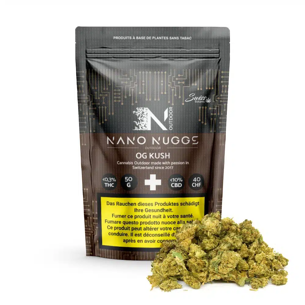 Cbd exterior nano nuggs - og kush - flores 1 Detrás de los cogollos de cannabis secos se muestra una bolsa negra resellable con la etiqueta "cbd exterior nano nuggs - og kush - flores", que muestra información sobre el thc, el cbd, el peso y el precio, junto con una advertencia sanitaria multilingüe.