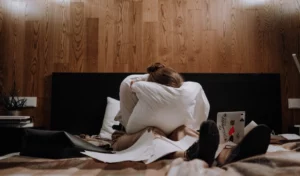 Un homme et une femme assis sur un lit avec des oreillers.