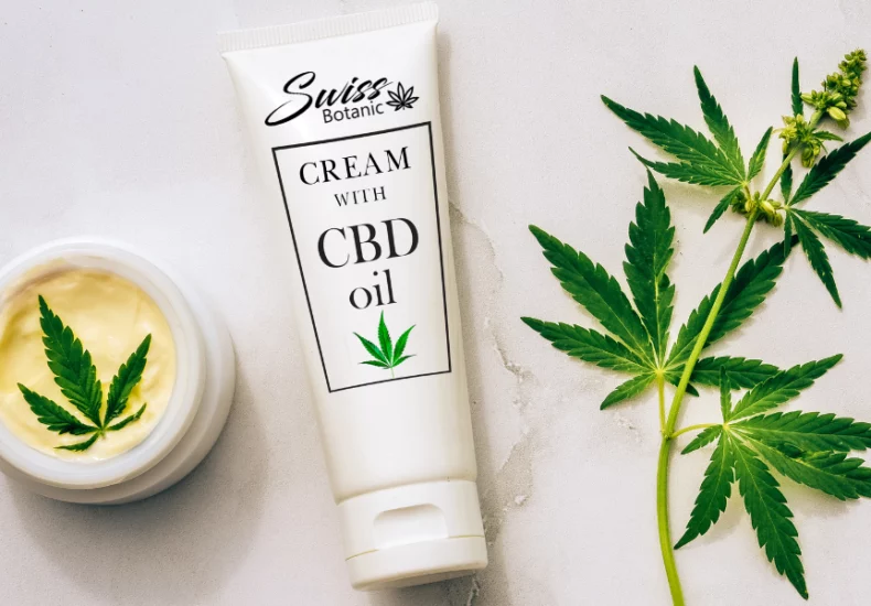 A tube of cream with cbd oil next to a plant.