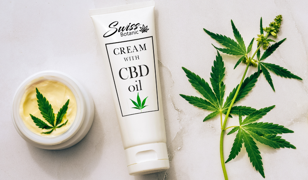 A tube of cream with cbd oil next to a plant.