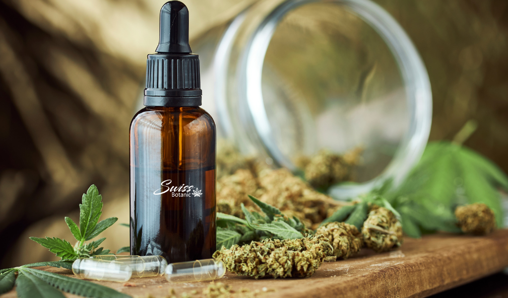 Une bouteille d'huile de CBD à côté des feuilles de cannabis.