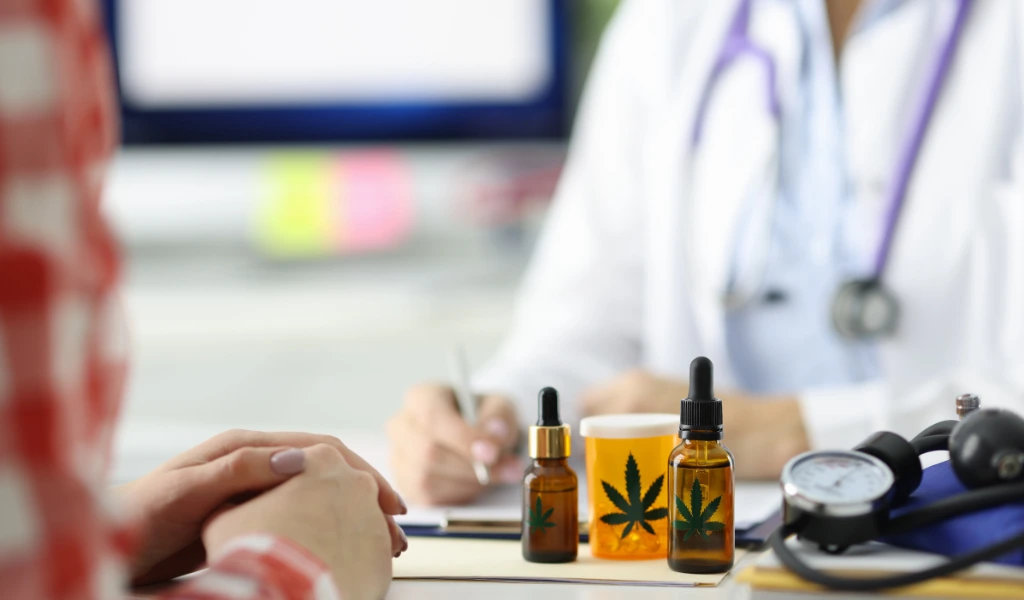 A woman is sitting at a desk with a stethoscope and cbd oil.