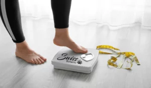 A woman's feet on a scale with a tape measure.