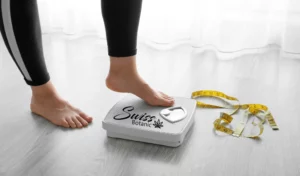 Los pies de una mujer sobre una báscula con cinta métrica.