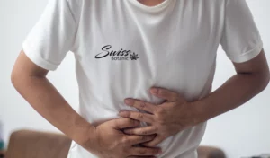 Un hombre sosteniendo su estómago con una camiseta blanca.