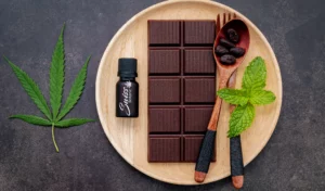 Cbd chocolate bar with mint leaves on a wooden plate.