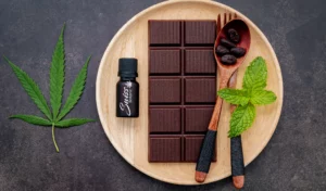 Barre de chocolat CBD avec feuilles de menthe sur une assiette en bois.