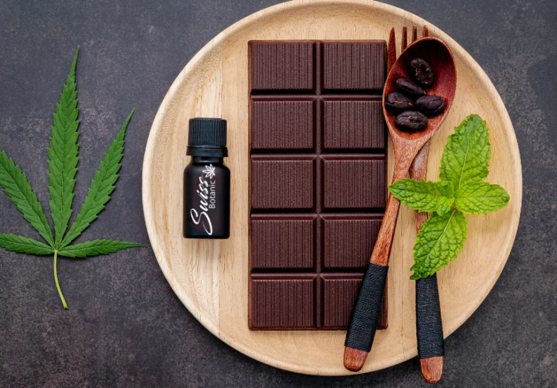 Cbd chocolate bar with mint leaves on a wooden plate.