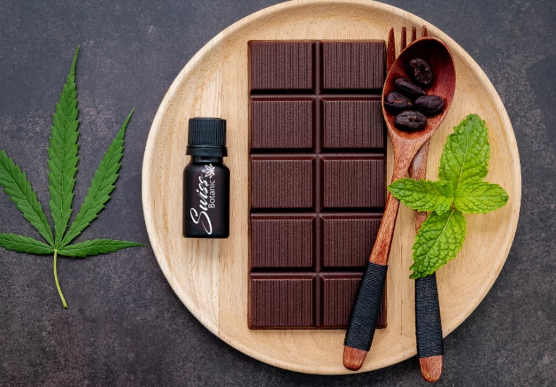 Chocolat au cbd 1 Barre de chocolat cbd avec feuilles de menthe sur une assiette en bois.