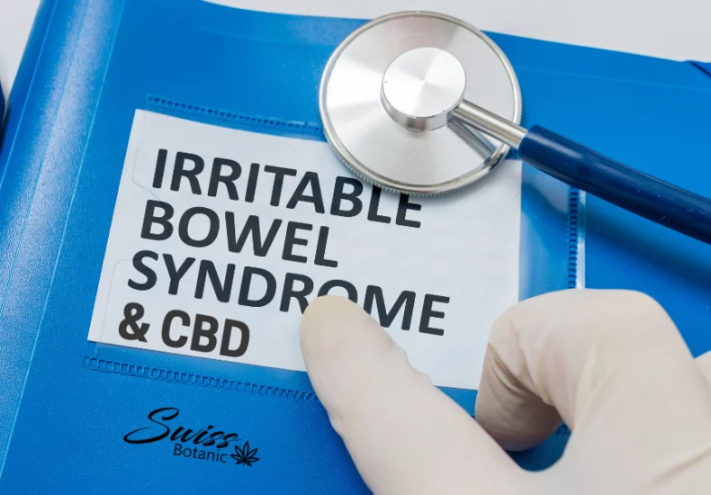 A gloved hand rests on a blue folder with a stethoscope, alongside a printed paper that reads "irritable bowel syndrome & cbd.