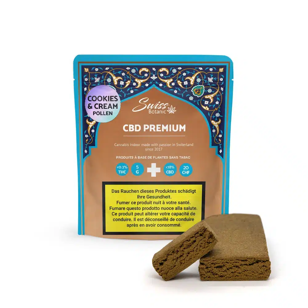 A package labeled "Cookies & Cream Pollen Premium - 0.3% THC" is displayed behind two pieces of brown cookies & cream CBD hash, with multiple warning labels in different languages.