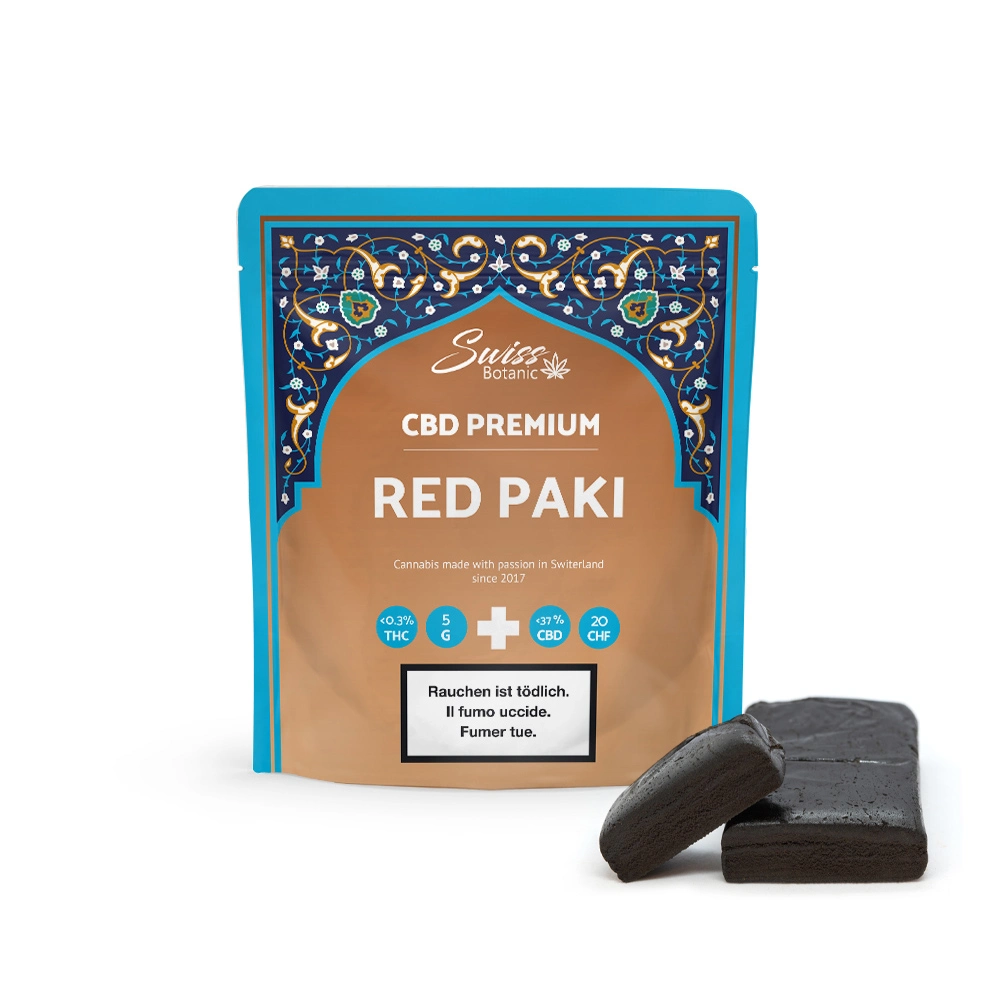 Un paquete etiquetado "Swiss Botanic CBD Premium Red Paki" con patrones decorativos, junto a dos losas de sustancia oscura.